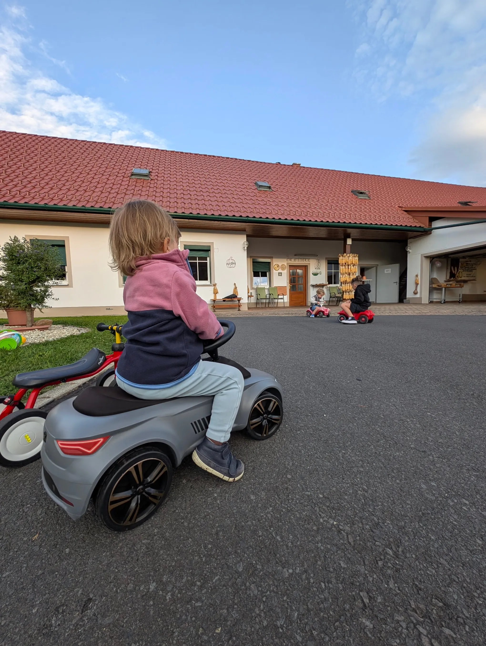 Kind fährt mit dem Bobbycar über den Hof Majczan